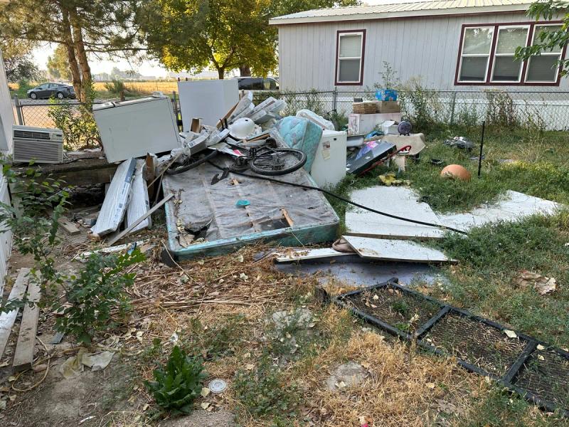 Yard debris and mattress outside a mobile home during an eviction cleanout in Eagle Idaho