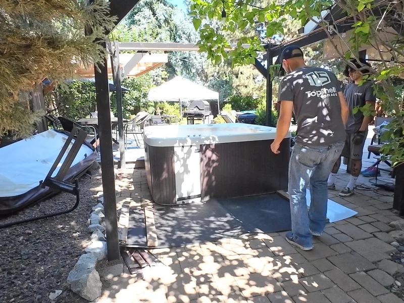 Top Shelf crew assessing a hot tub on a patio under a pergola before removal in Caldwell Idaho