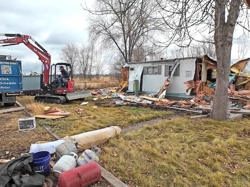 Top Shelf excavator demolishing a mobile home with branded truck on site in Caldwell Idaho