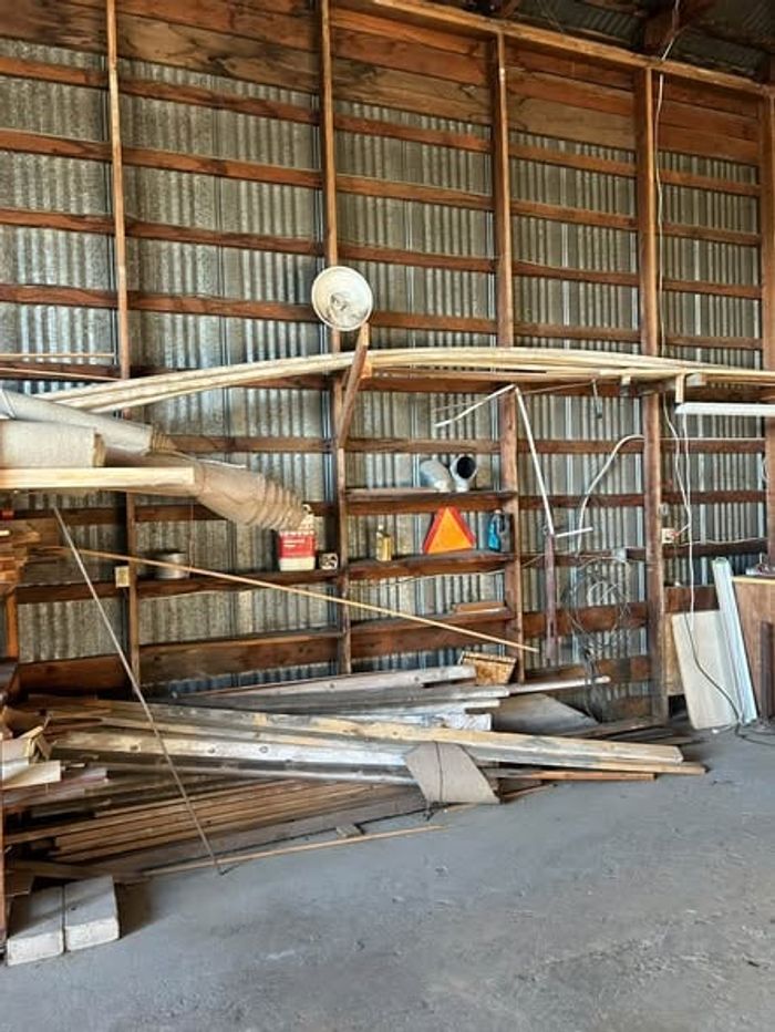 Stacks of scrap lumber and leftover building materials piled inside a metal shop