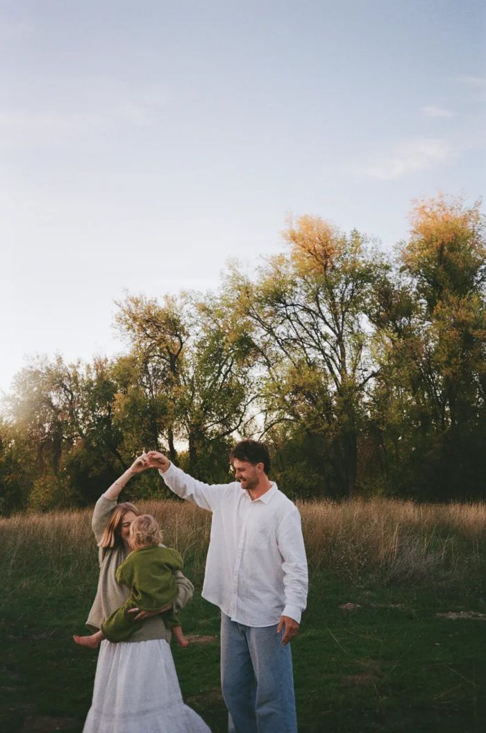 Tommy Simonson of Man of Steel Junk Removal dancing with his wife in a field at sunset near Eagle, Idaho, their little one in her arms