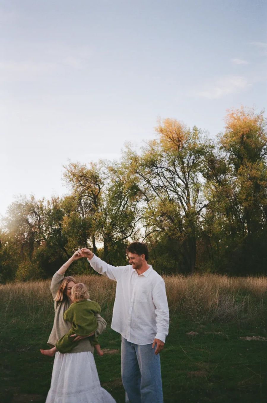 Tommy Simonson of Man of Steel Junk Removal dancing with his wife in a field at sunset near Eagle, Idaho, their little one in her arms