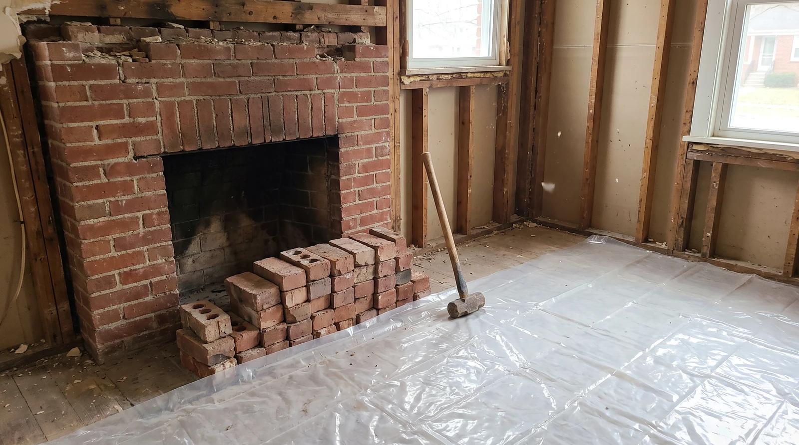 Partially removed brick fireplace with salvaged bricks stacked on a protected floor during a fireplace demolition in a Boise, Idaho home