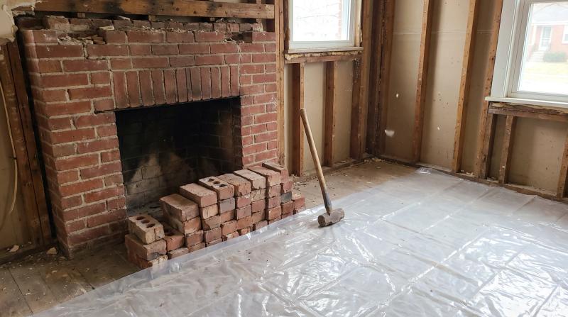 Partially removed brick fireplace with salvaged bricks stacked on a protected floor during a fireplace demolition in a Boise, Idaho home