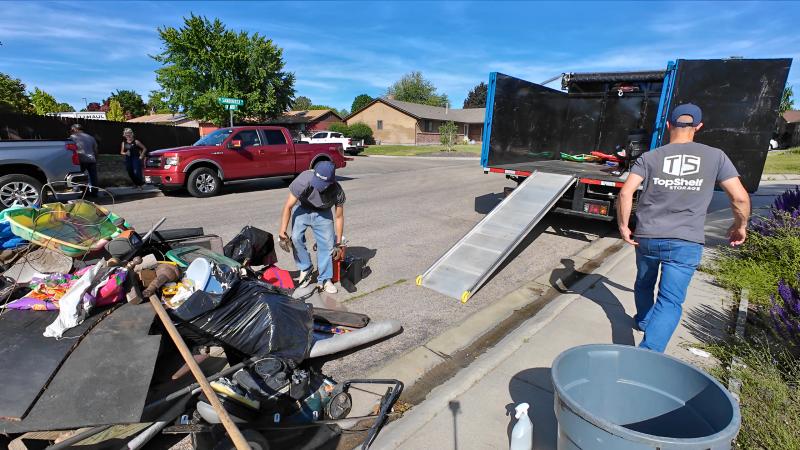 Top Shelf crew loading a curbside pile of household junk and clutter into the branded truck in a neighborhood in Garden City Idaho