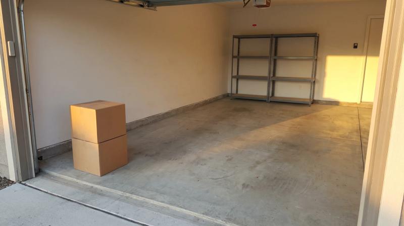 Half-cleared garage in Eagle, Idaho with a few boxes by the open door and empty metal shelving during a garage cleanout