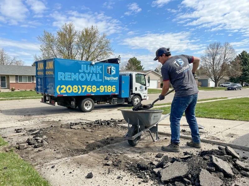 Top Shelf crew member loading broken asphalt into the junk removal truck in Eagle Idaho