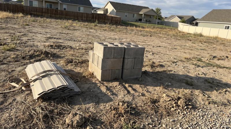 Stacked concrete pier blocks and folded vinyl skirting panels on a cleared mobile home lot in Nampa, Idaho after demolition