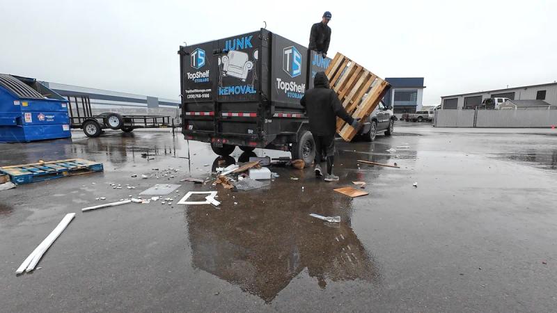 Top Shelf crew loading broken wooden pallets into the branded trailer during a commercial pallet removal job at an industrial park in Meridian Idaho