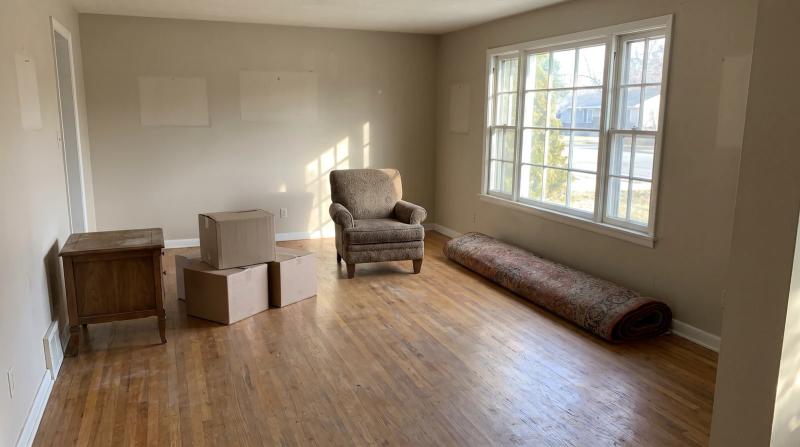 Leftover boxes, an armchair and a rolled rug in an emptied living room after an estate sale in Meridian, Idaho