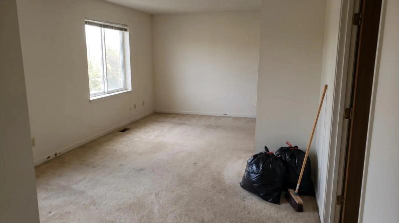 Empty rental home living room in Star, Idaho after a cleanout, with a few tied trash bags and a push broom near the doorway