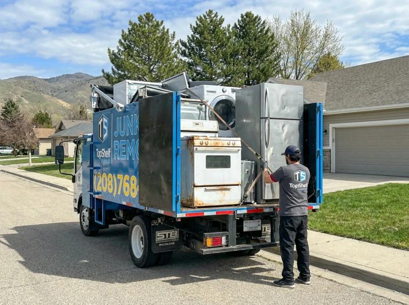 Top Shelf crew member loading oven into the junk removal truck in Garden City Idaho