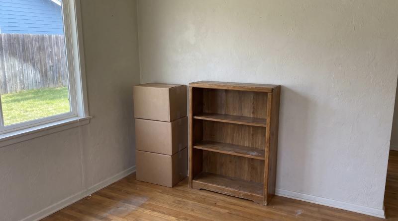 Labeled moving boxes and an empty bookshelf during an estate cleanout in a Caldwell, Idaho home.