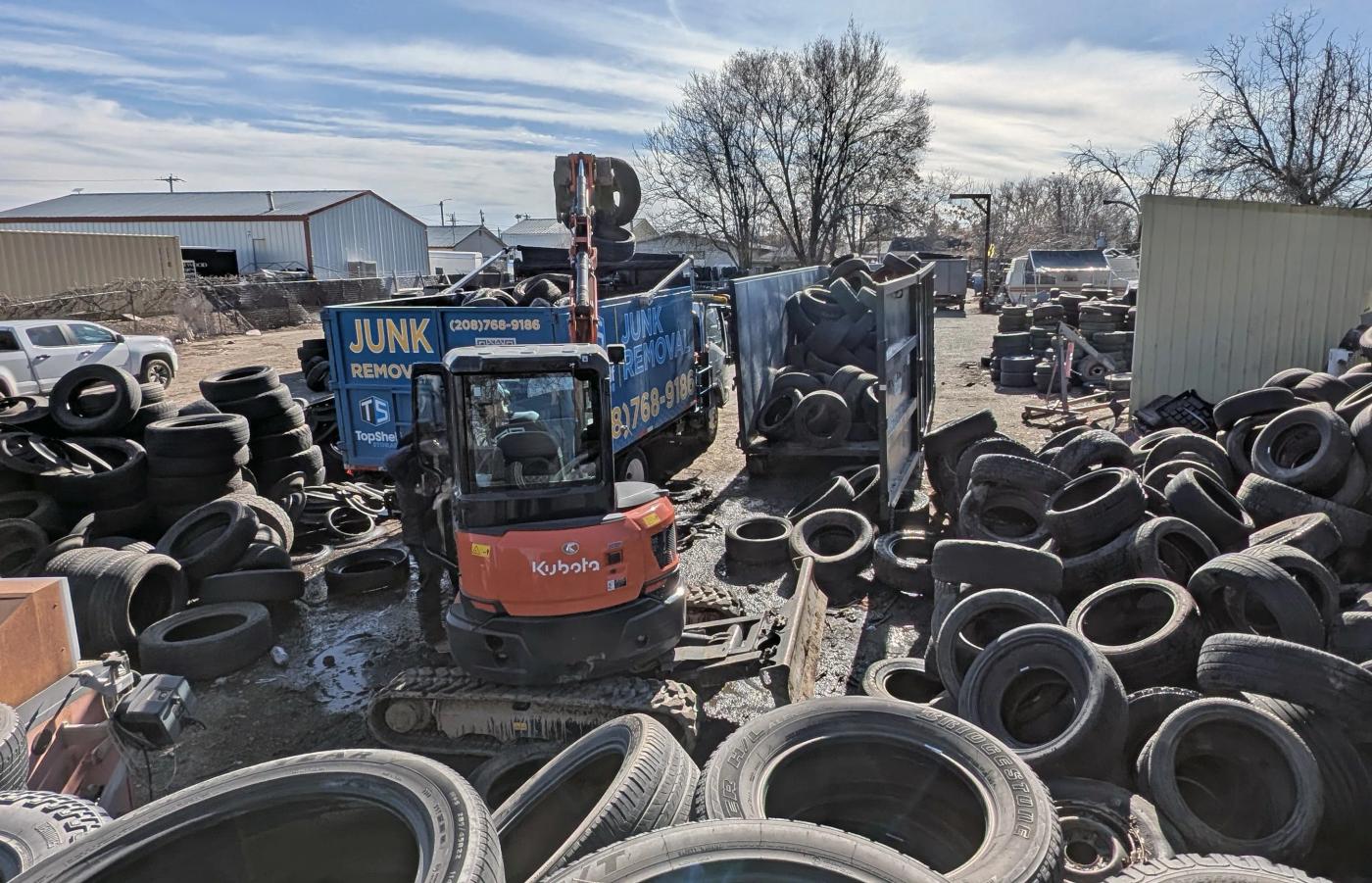 Top Shelf excavator and branded truck handling tire removal at a yard in the Boise Idaho area