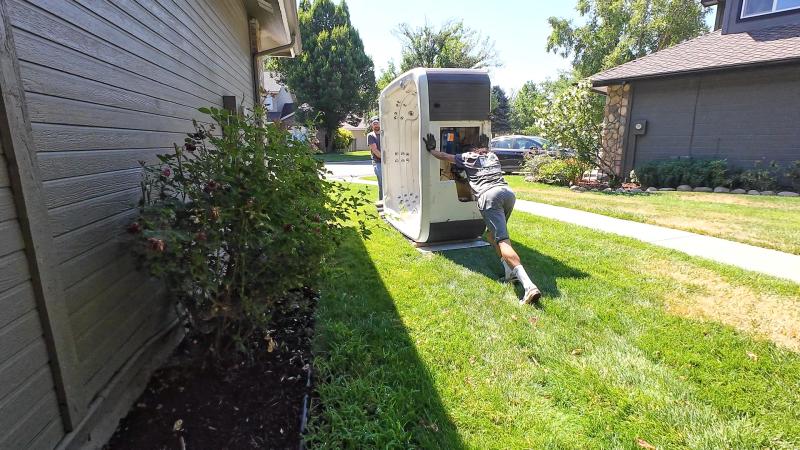 Top Shelf crew member pushing a hot tub on its side through a residential side yard during removal in Caldwell Idaho