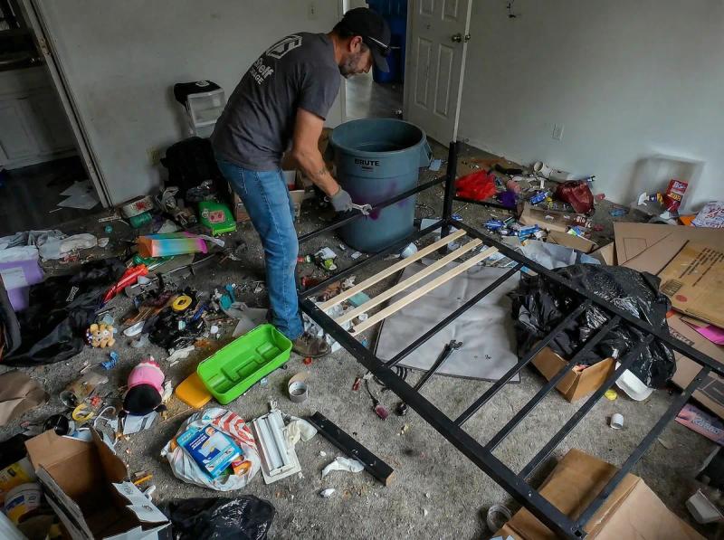 Top Shelf employee clearing debris and a bed frame from a hoarded bedroom in Nampa Idaho