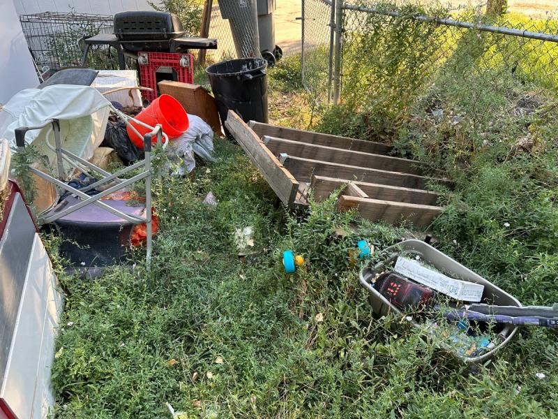 Overgrown yard with junk and debris from an eviction cleanout