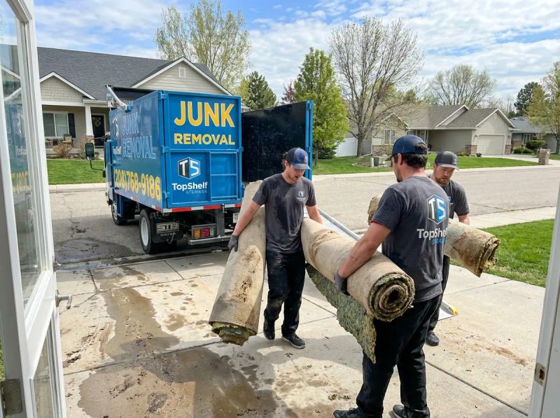 Top Shelf crew member loading restoration debris into the junk removal truck in Emmett Idaho