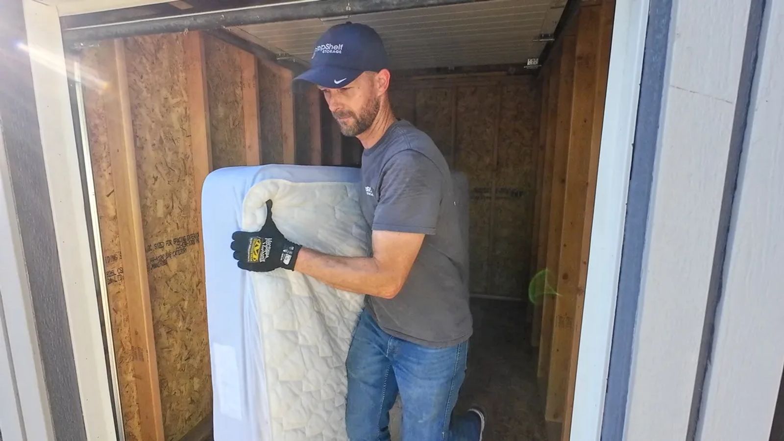 Top Shelf crew member carrying a mattress out of a shed during a cleanout job in Kuna Idaho
