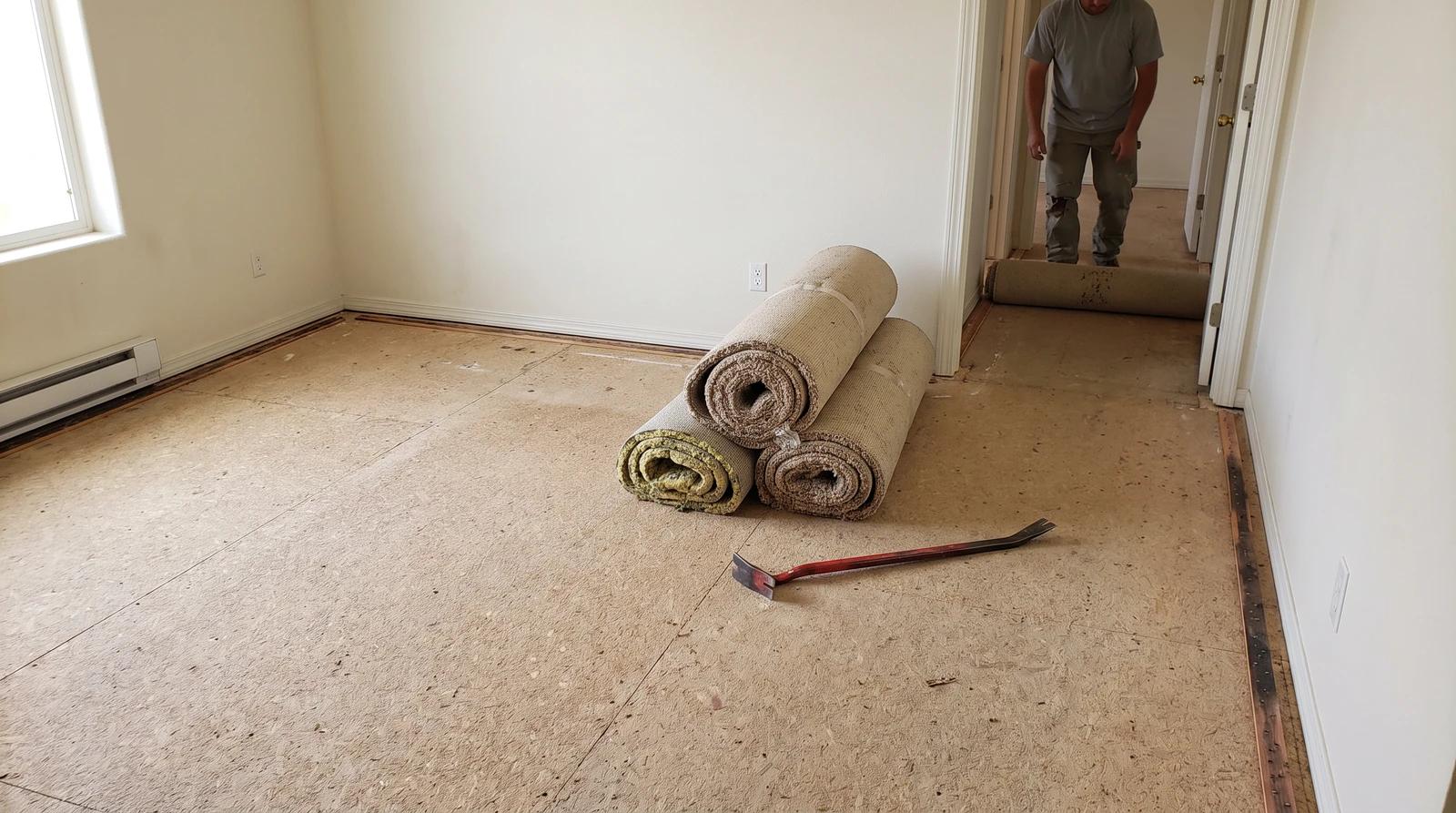 Old carpet rolled up on a bare particleboard subfloor during mobile home carpet removal in Garden City, Idaho