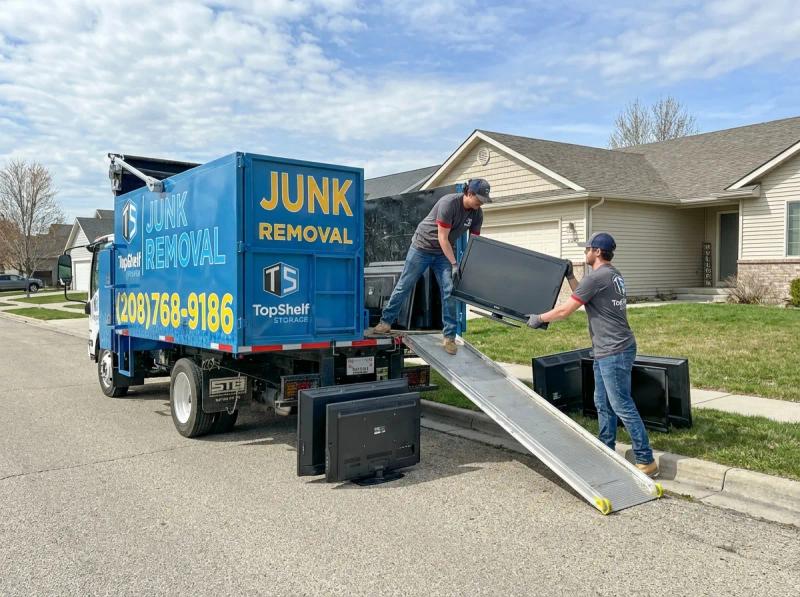 Top Shelf junk removal team hauling a television to the branded truck in Boise Idaho
