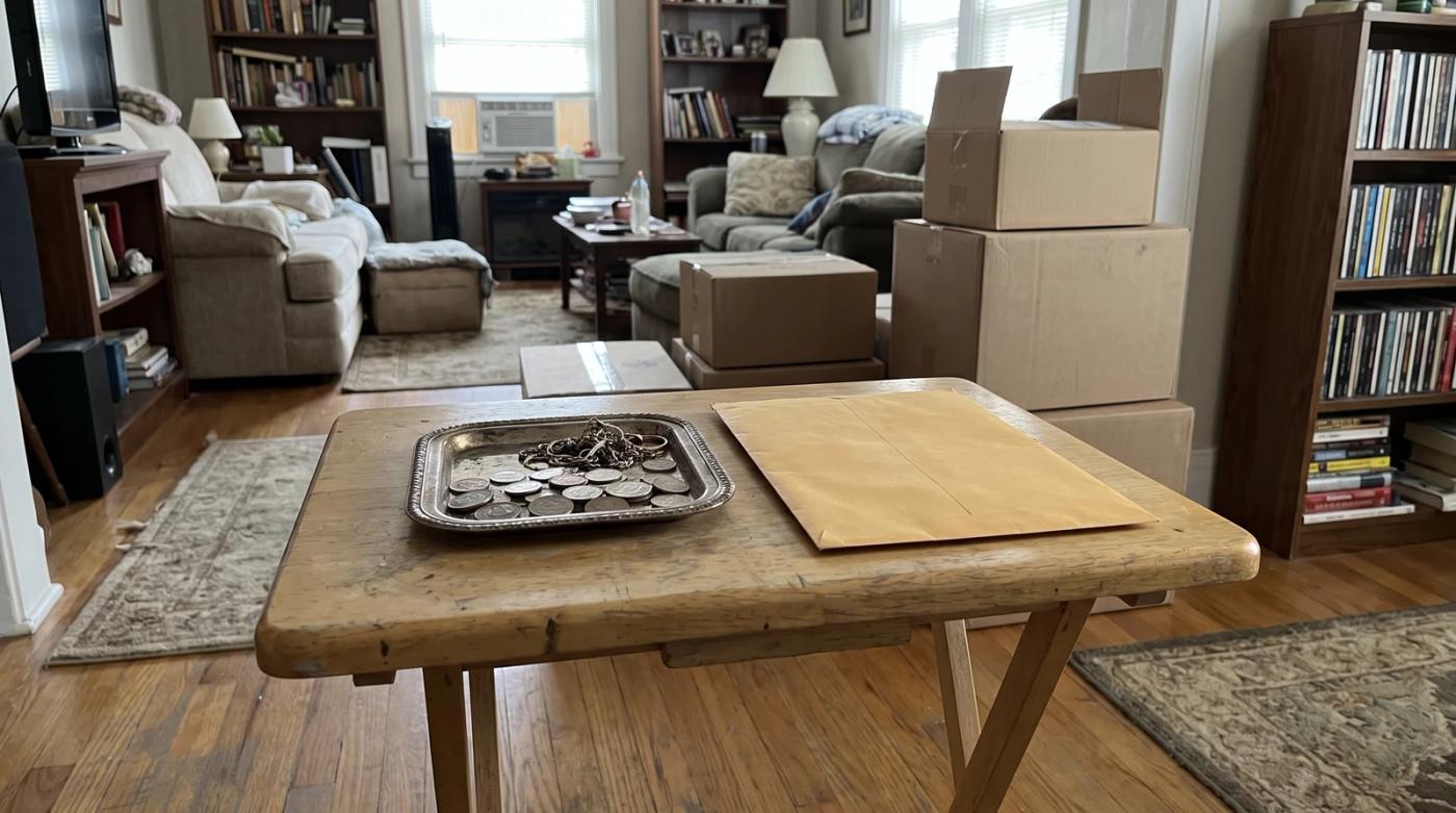 Sorting table with coins, jewelry, and an envelope set aside during a hoarding cleanup in a Meridian, Idaho home
