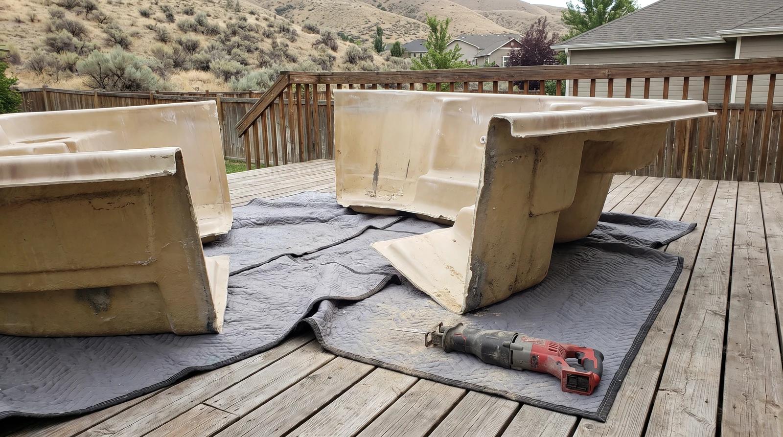 Hot tub cut into sections on moving blankets over a backyard wooden deck in Nampa, Idaho during removal
