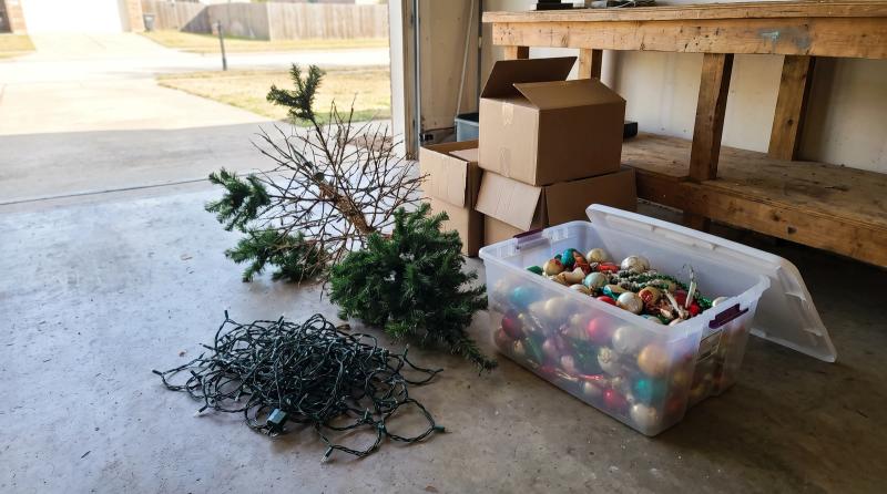 Old artificial Christmas tree, tangled string lights and a tote of faded ornaments sorted for junk removal in a Nampa, Idaho garage