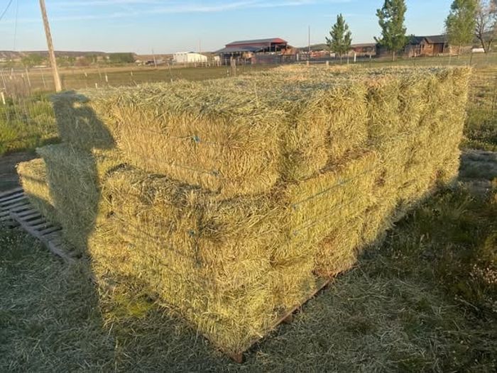 A tall, neat stack of hay bales in the evening light