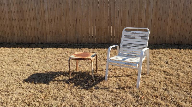 Weathered patio chair and rusted side table waiting for furniture removal in a Kuna, Idaho backyard