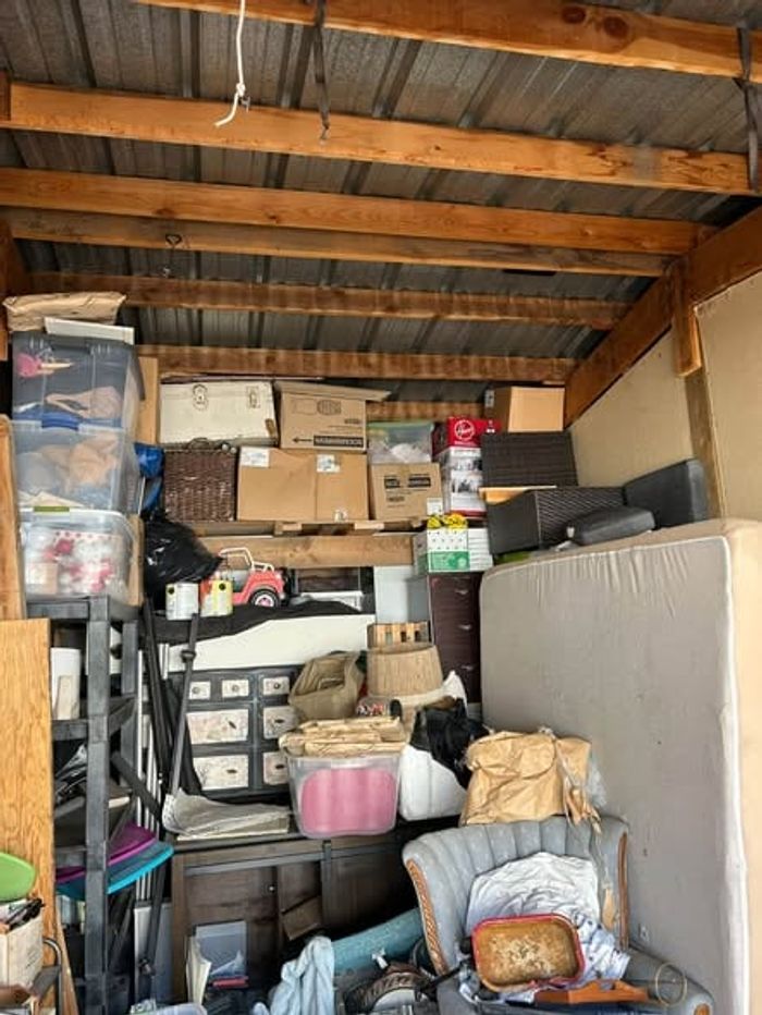 A storage unit stacked with boxes, a mattress and household goods before a cleanout