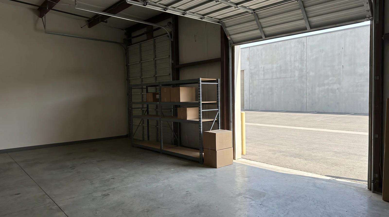 Commercial warehouse unit in Eagle, Idaho with a bare concrete floor, stacked boxes and steel shelving by an open roll-up door