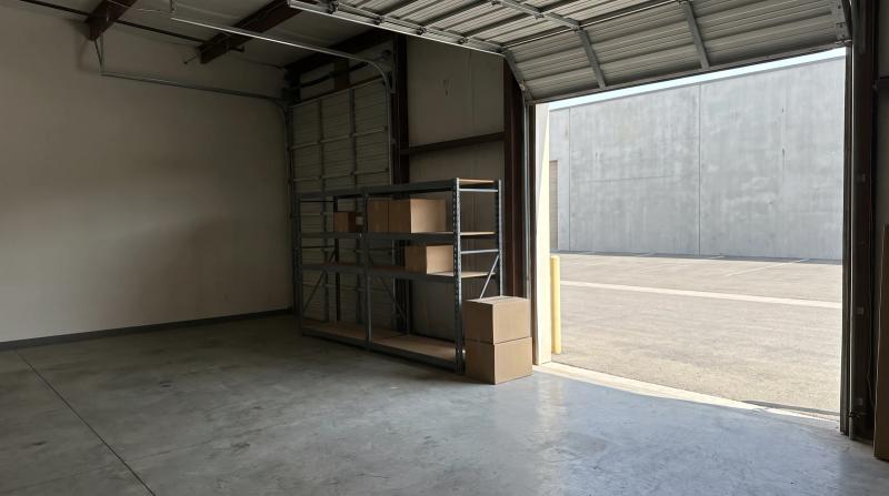 Commercial warehouse unit in Eagle, Idaho with a bare concrete floor, stacked boxes and steel shelving by an open roll-up door