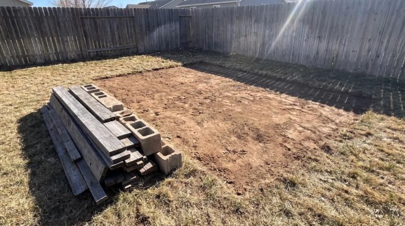 Bare dirt and a neat stack of old shed boards and concrete blocks after a shed demolition in a Nampa, Idaho backyard