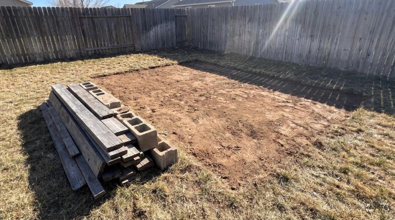Bare dirt and a neat stack of old shed boards and concrete blocks after a shed demolition in a Nampa, Idaho backyard