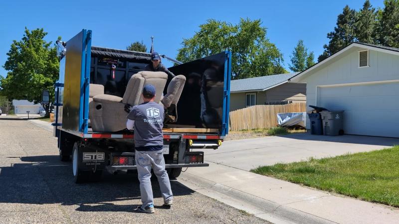 Top Shelf crew member loading a recliner chair into the junk removal truck