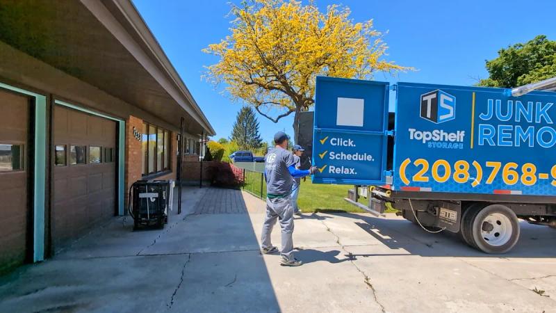 Top Shelf junk removal crew loading dishwasher onto branded truck in Boise Idaho driveway