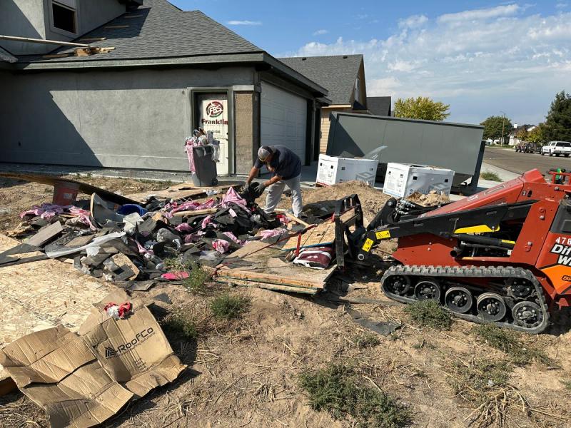 Skid steer cleaning up construction debris at a job site in the Boise Idaho area