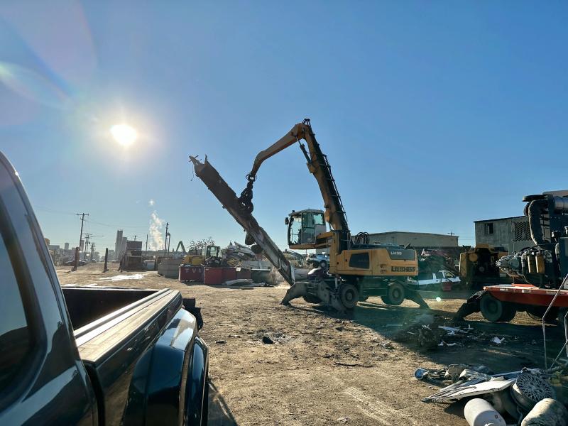 Material handler lifting a large piece of scrap metal at a recycling yard after a Top Shelf scrap metal removal job in Garden City Idaho