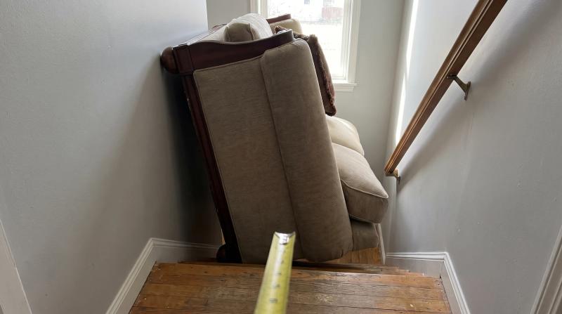 A bulky sofa tilted sideways on a tight staircase landing during a furniture removal job at a home in Star, Idaho