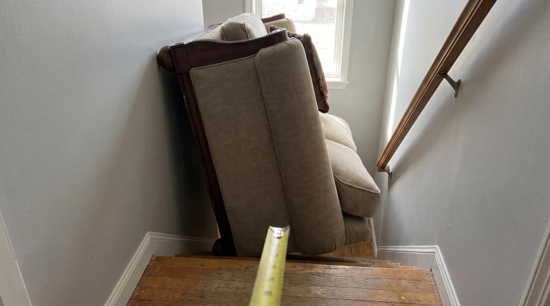 A bulky sofa tilted sideways on a tight staircase landing during a furniture removal job at a home in Star, Idaho