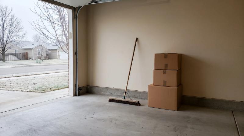 Cleared-out garage floor with a push broom and stacked boxes on a frosty fall morning in Middleton, Idaho