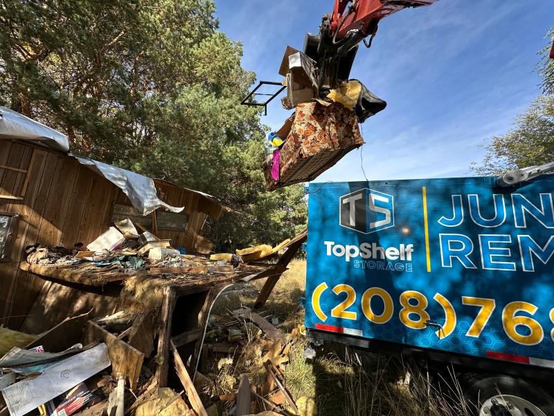 Top Shelf excavator grapple arm clearing debris from a demolished structure during a land clearing job in Caldwell Idaho