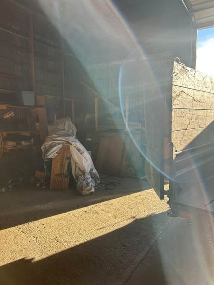 Bagged items and leftover clutter by the open door of a shop during a cleanout