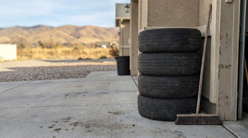 Four worn tires with cracked sidewalls stacked in a garage in Star, Idaho, waiting for old tire removal