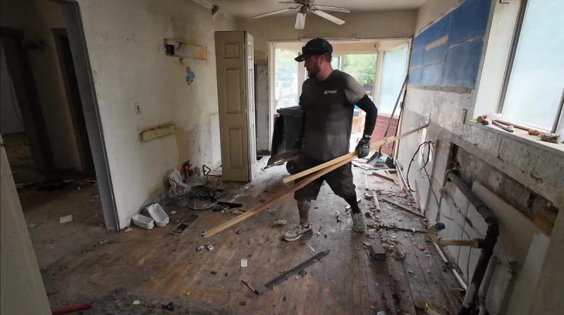 Top Shelf crew member carrying lumber and construction debris out of a gutted house during a renovation cleanout in Meridian Idaho