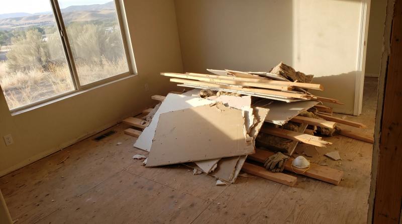 Pile of drywall scraps and lumber left on a bare subfloor after a home remodel in Kuna, Idaho, ready for construction cleanup.