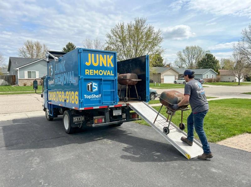 Top Shelf junk removal team hauling a BBQ grill to the branded truck in Meridian Idaho