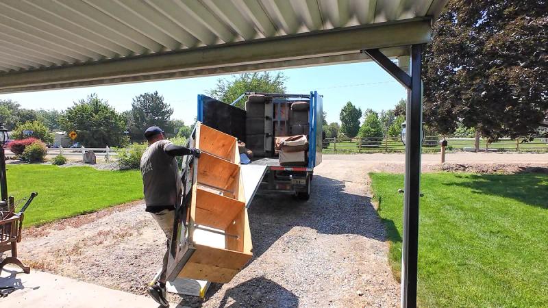 Top Shelf crew loading a dresser from under a carport into the truck