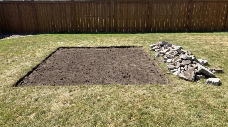 Bare graded dirt where a concrete patio was removed in a Meridian, Idaho backyard, with broken concrete chunks stacked neatly along one edge